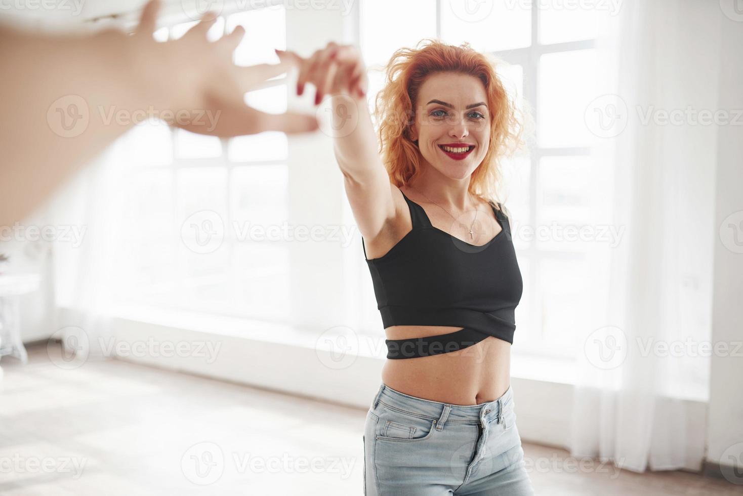 Spending time together. Attractive redhead woman posing in the spacey room near the window photo