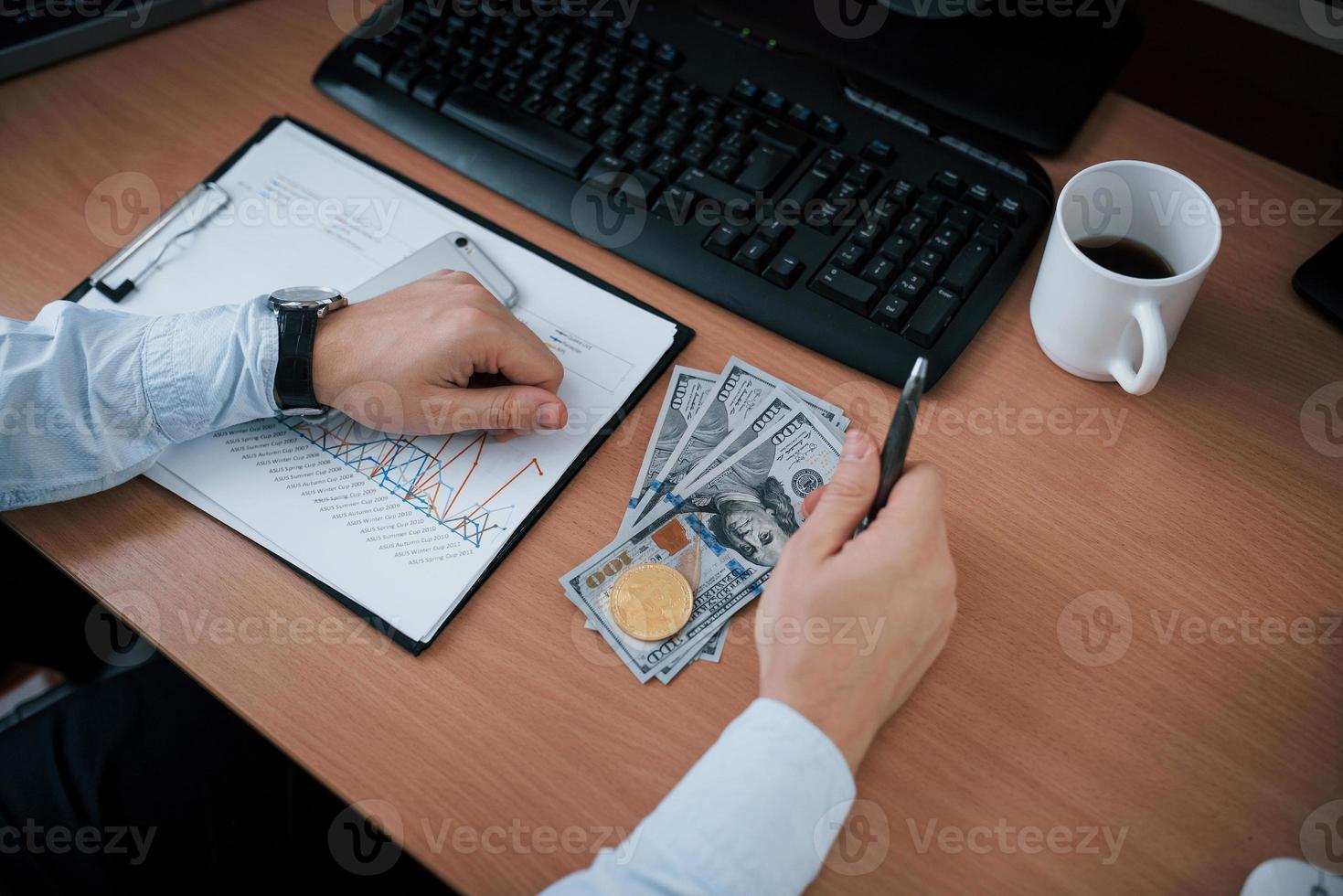 Top view of money and bitcoin. Man working online in the office with multiple computer screens in index charts photo