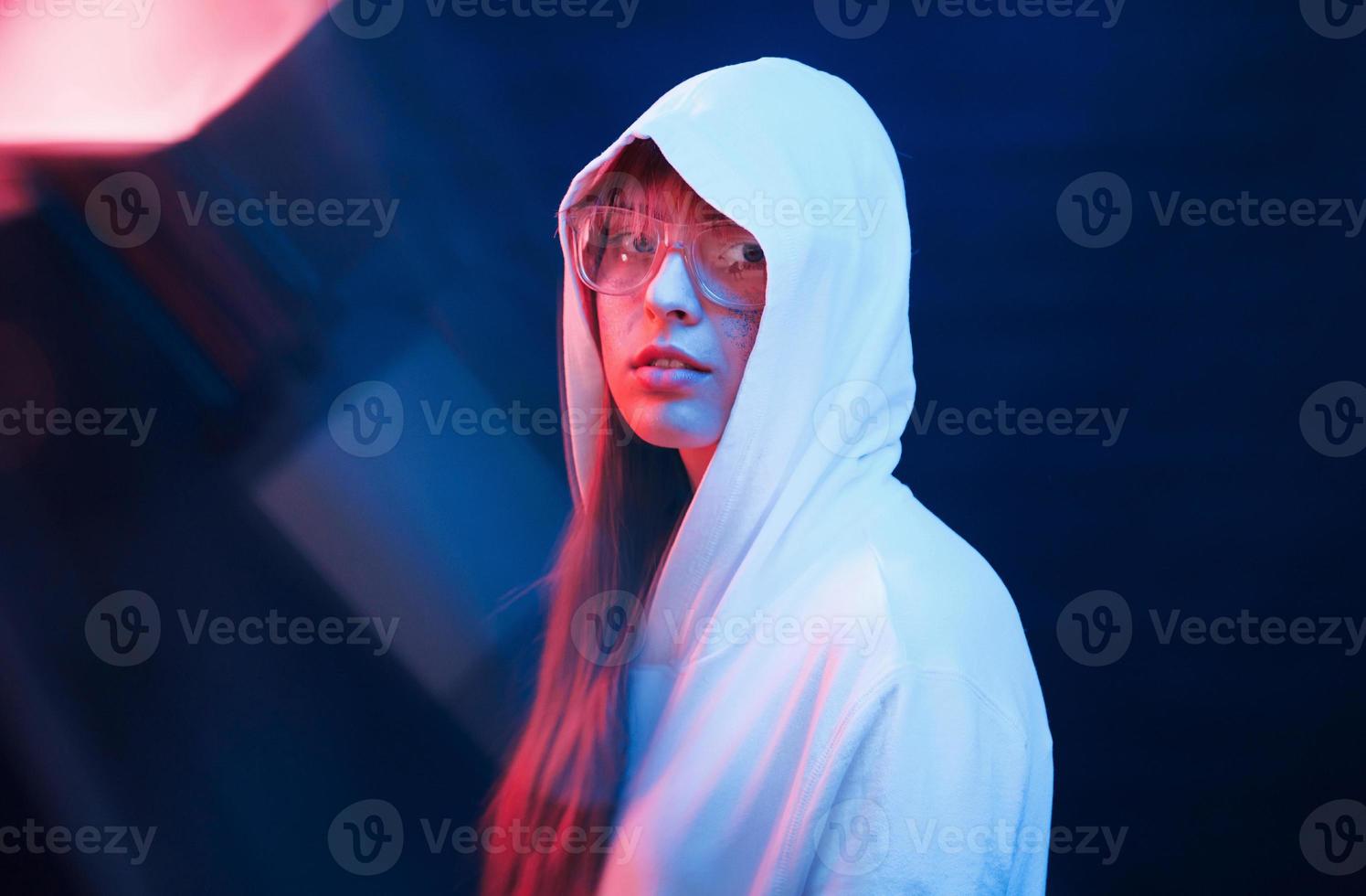 Modern look of youth. Studio shot in dark studio with neon light. Portrait of young girl photo