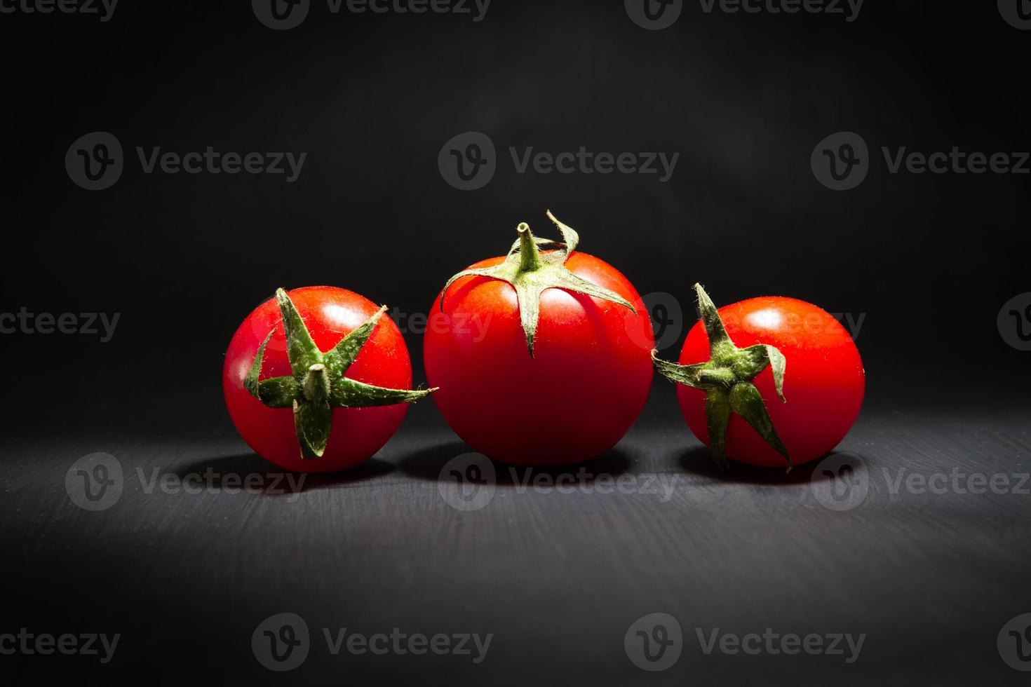 Red cherry tomatoes isolated on black photo