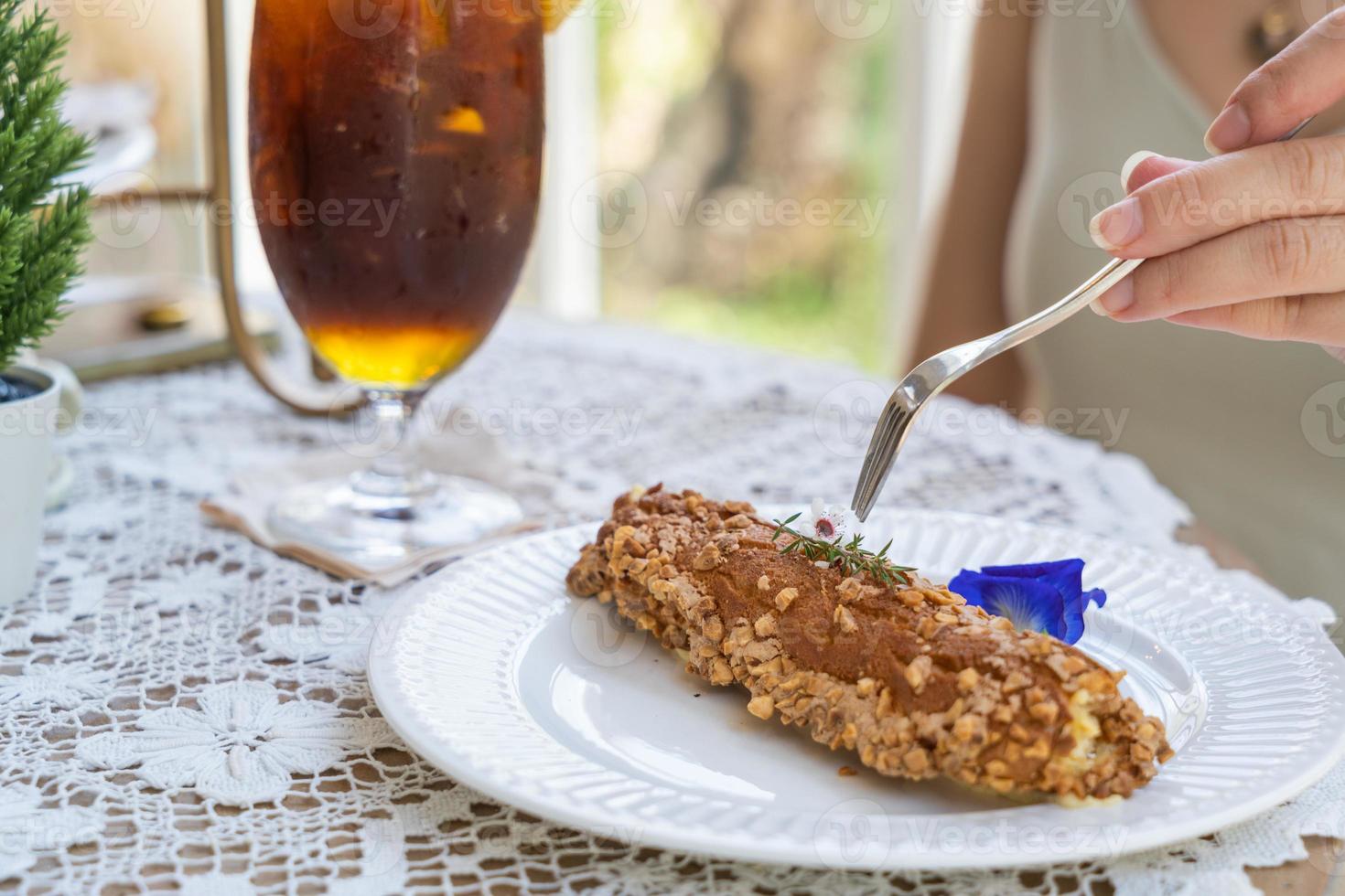 Homemade puff pastry deep fried Eclairs with vanilla cream topping with almonds nut on white plate over table top with lace tablecloth. traditional french dessert. selective focus photo