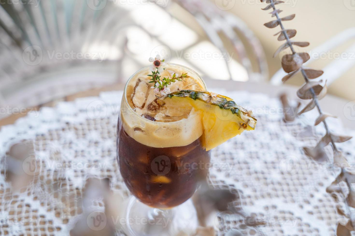 selective focus, Glass of iced drink on table, summer cocktail recipe, refreshment concept. Cold drink Black Coffee is the New exotic Iced Coffee With Pineapple Juice. photo