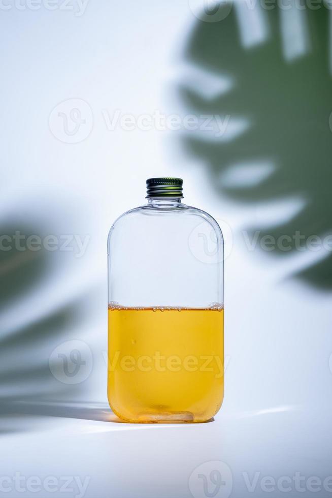 drink in a glass bottle on white background with hard or Harsh shadows and sunlight of leaves tree branch falling on wall. modern and minimal product design. cold refreshment beverage. photo