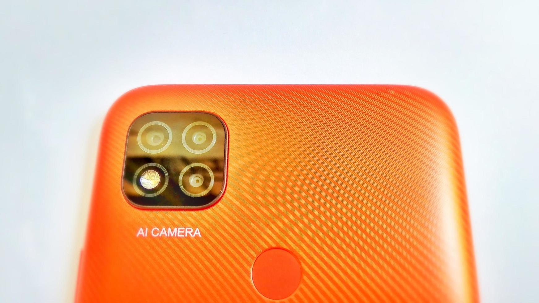Cirebon Indonesia, April 2022. Orange smartphone of Redmi 9C model with Artificial Intelligence cameras isolated under white gray background. Suitable for company and industry advertising, etc. photo