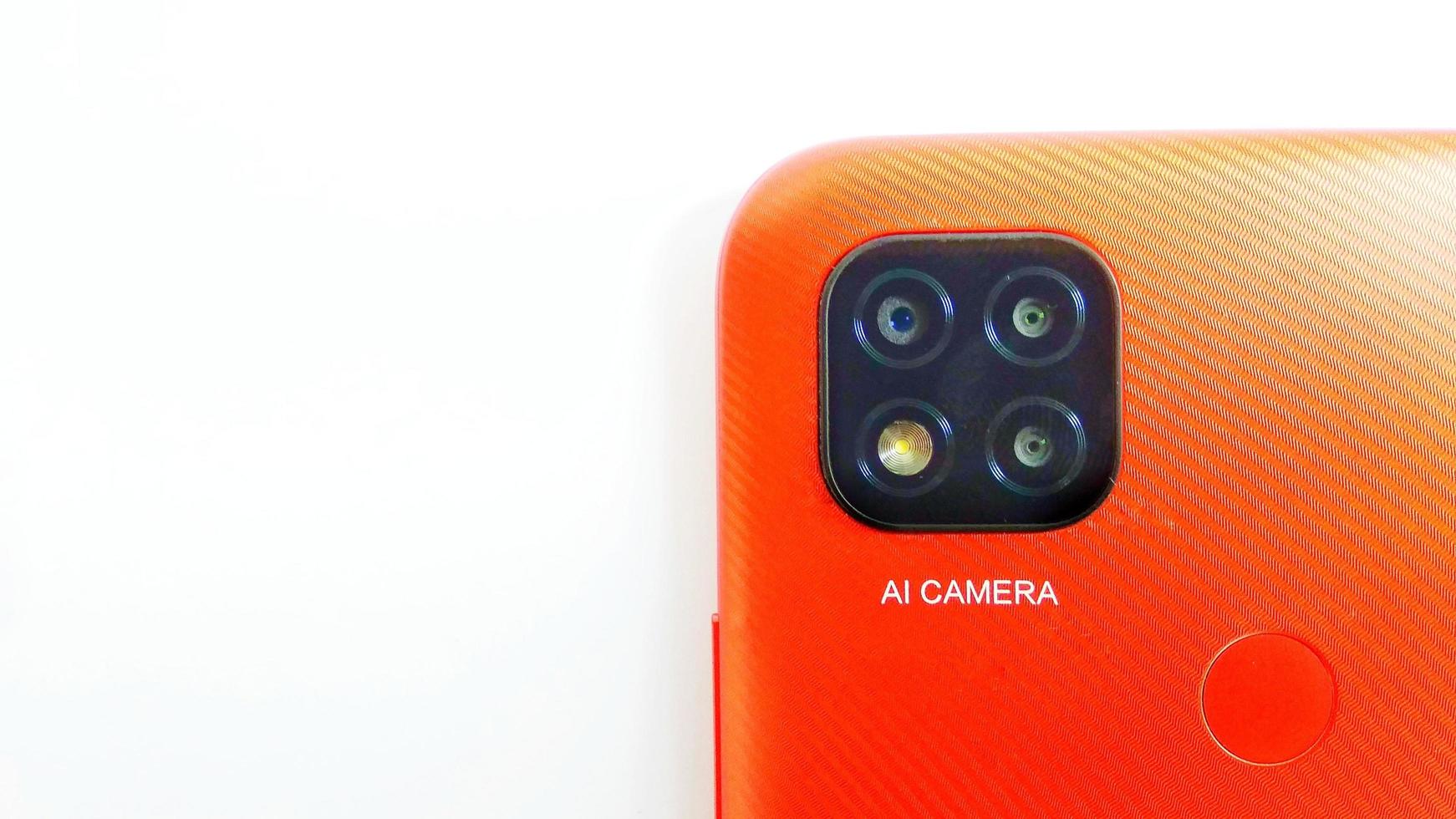Cirebon Indonesia, April 2022. Orange smartphone of Redmi 9C model with Artificial Intelligence cameras isolated under white gray background. Suitable for company and industry advertising, etc. photo