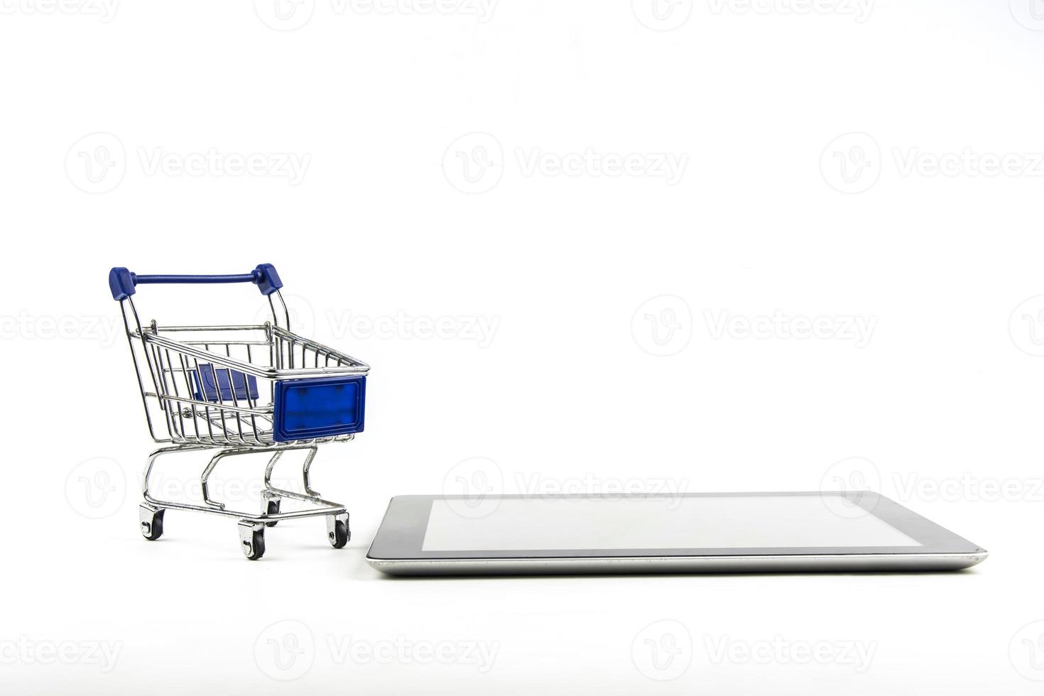 carrito de compras con tableta en backgrond blanco, significa comprar en línea foto