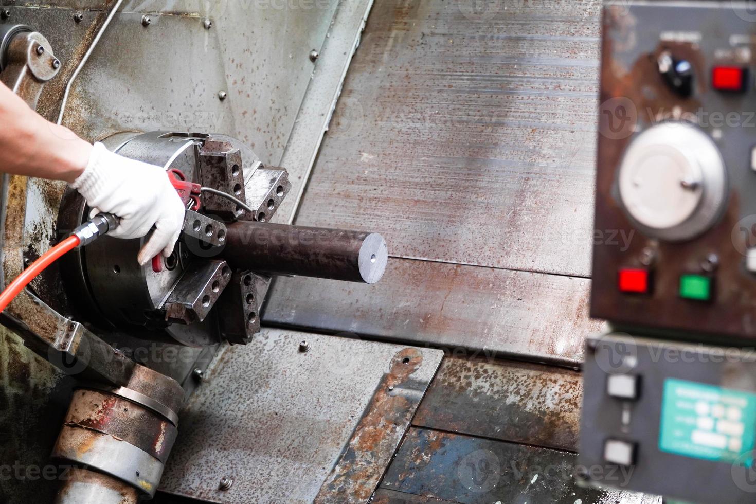 Man uses air gun to spray workpiece in cnc machine parts factory,Operator machining automotive part by cnc turning machine photo
