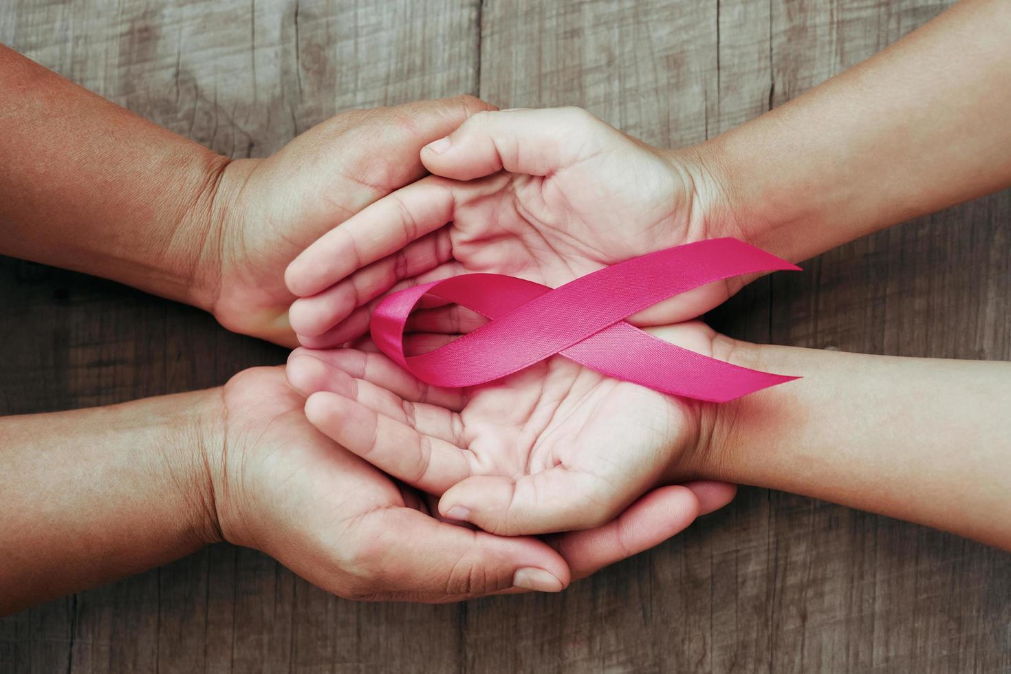 concepto de salud y medicina. mano que sostiene la cinta rosa en la madera. conciencia del cáncer de mama. señal de esperanza foto