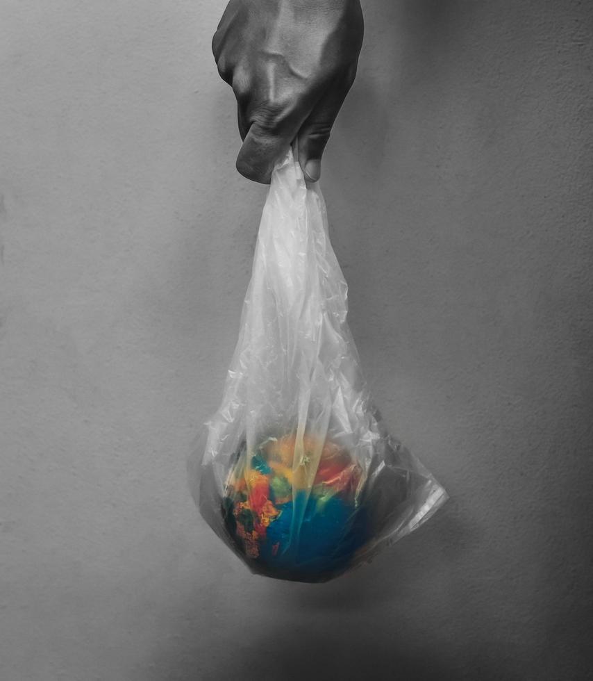 hand holding globe in plastic bag on black background concept earth day photo
