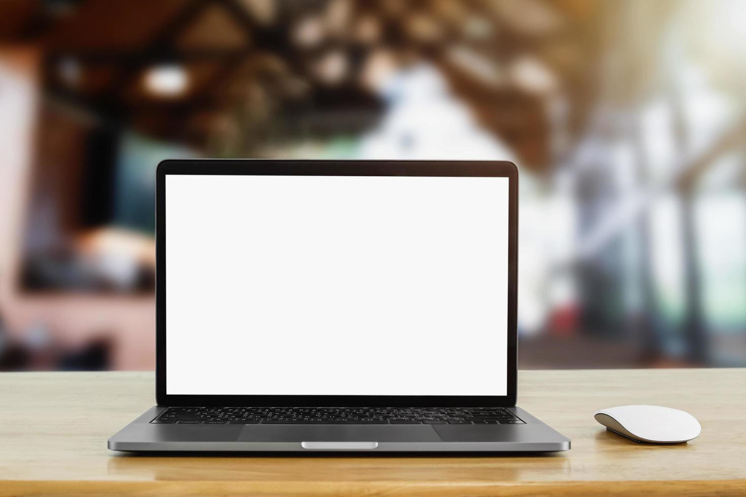laptop computer blank white screen on table in cafe background photo