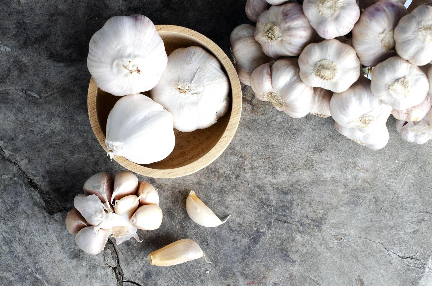 Garlic vegetable in wooden bowl on olds wood table backgrounds photo