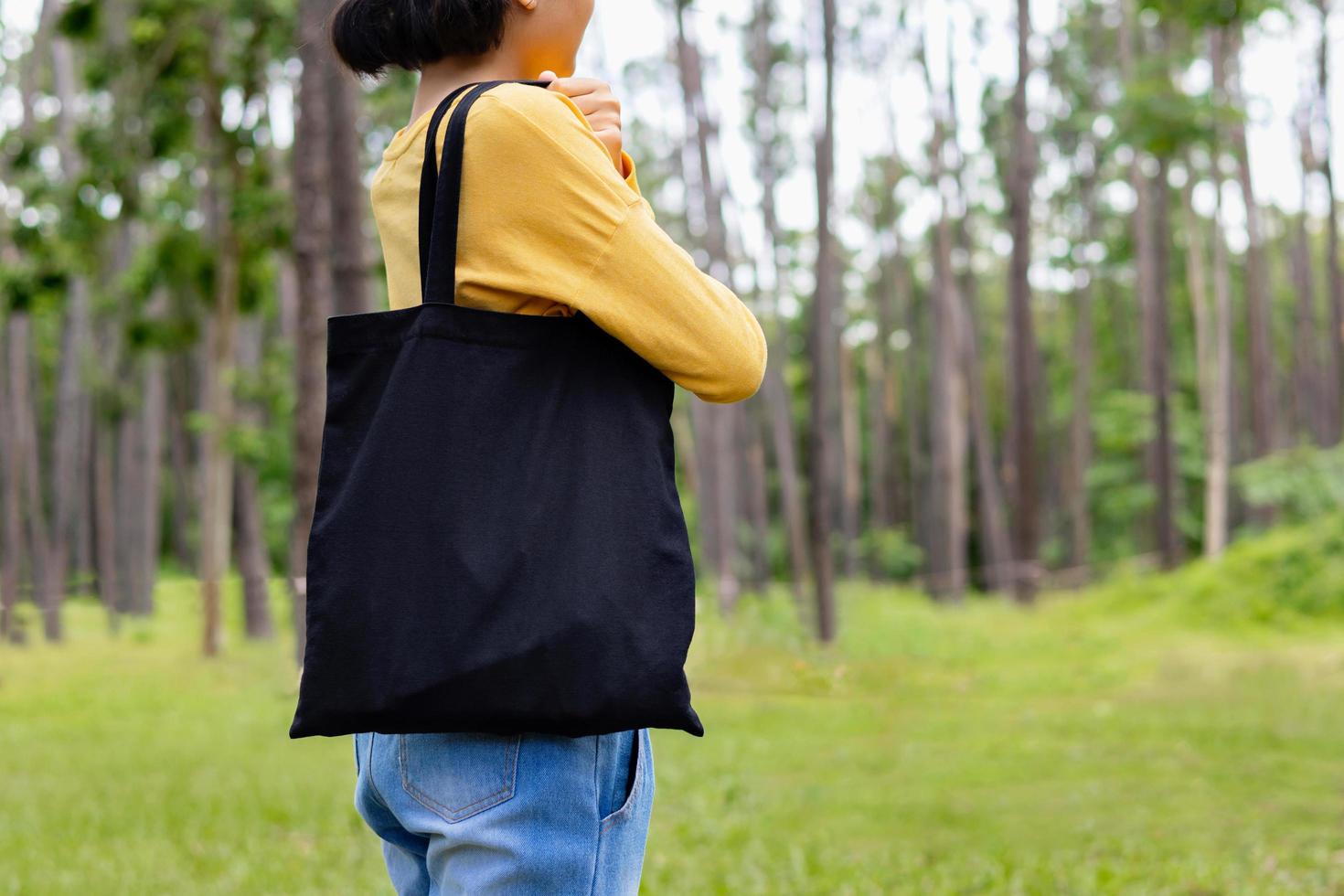 mujer sosteniendo una bolsa de algodón negro en el fondo de la naturaleza foto