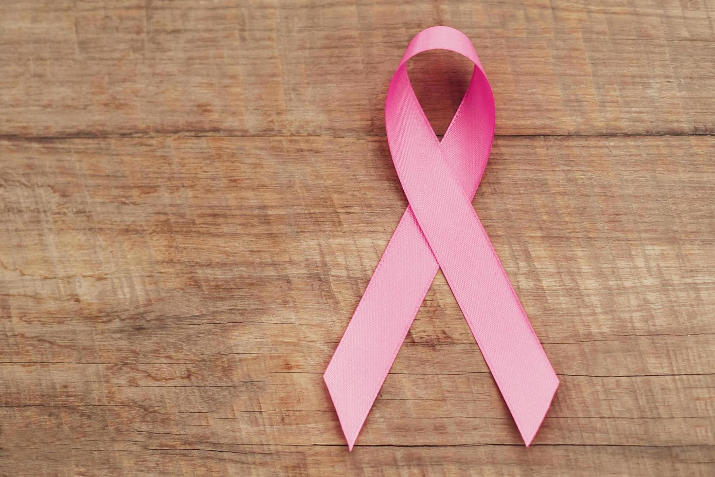 cinta rosa sobre madera. conciencia del cáncer de mama. concepto de salud y medicina foto