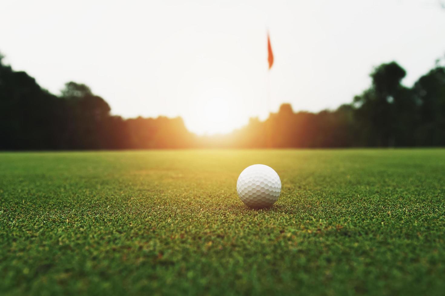 pelota de golf sobre hierba verde con agujero y luz solar foto