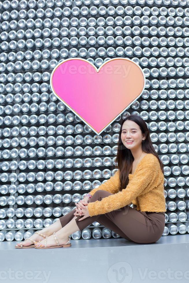 Asian beautiful woman with long hair is sitting and smiling in heart background as Valentine s  day concept. abstract background photo