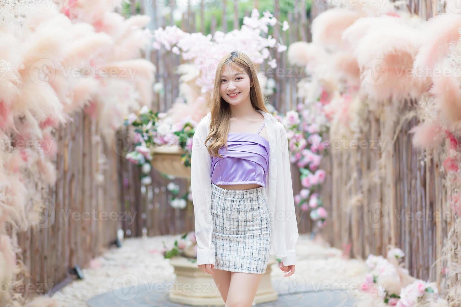 Asian beautiful woman with long bronze hair who wears short skirt and white long sleeve stands in the cafe garden. photo