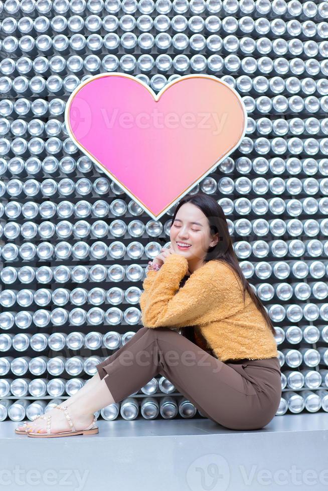 Asian pretty woman in long hair wears a yellow sweater and brightly smiles in Valentines theme. photo