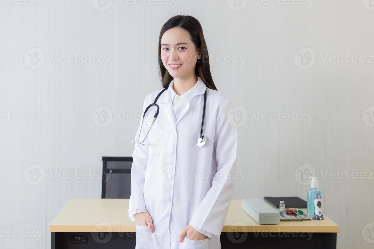 An Asian female doctor with a white lab coat standing and wearing a white robe  and  stethoscope. photo