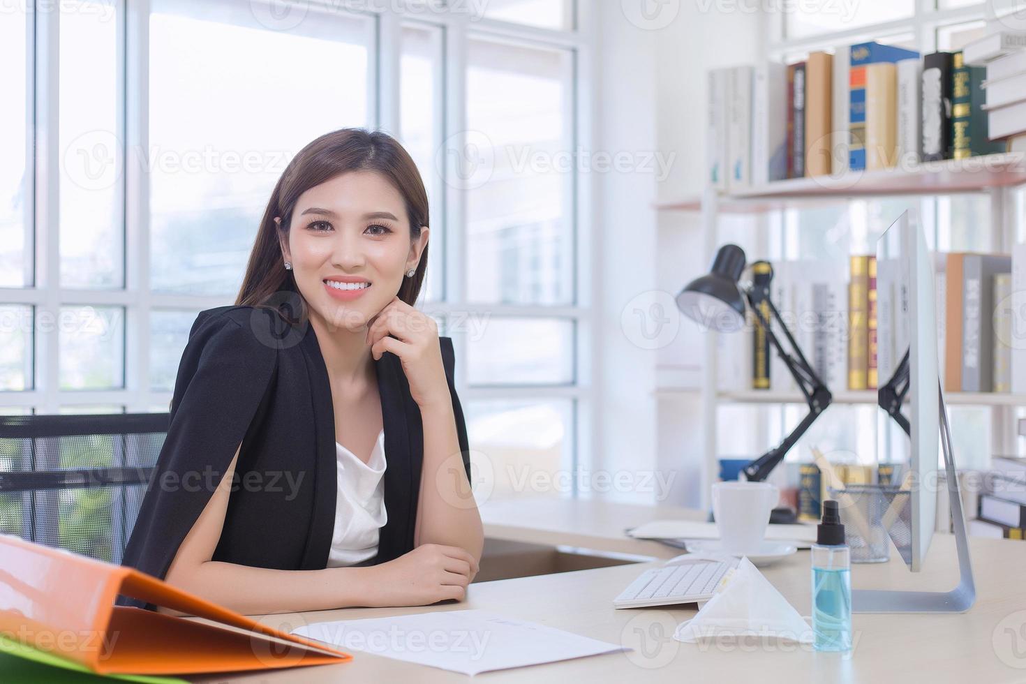 una hermosa mujer asiática trabaja en la oficina. en su escritorio tiene muchos archivos y documentos. foto