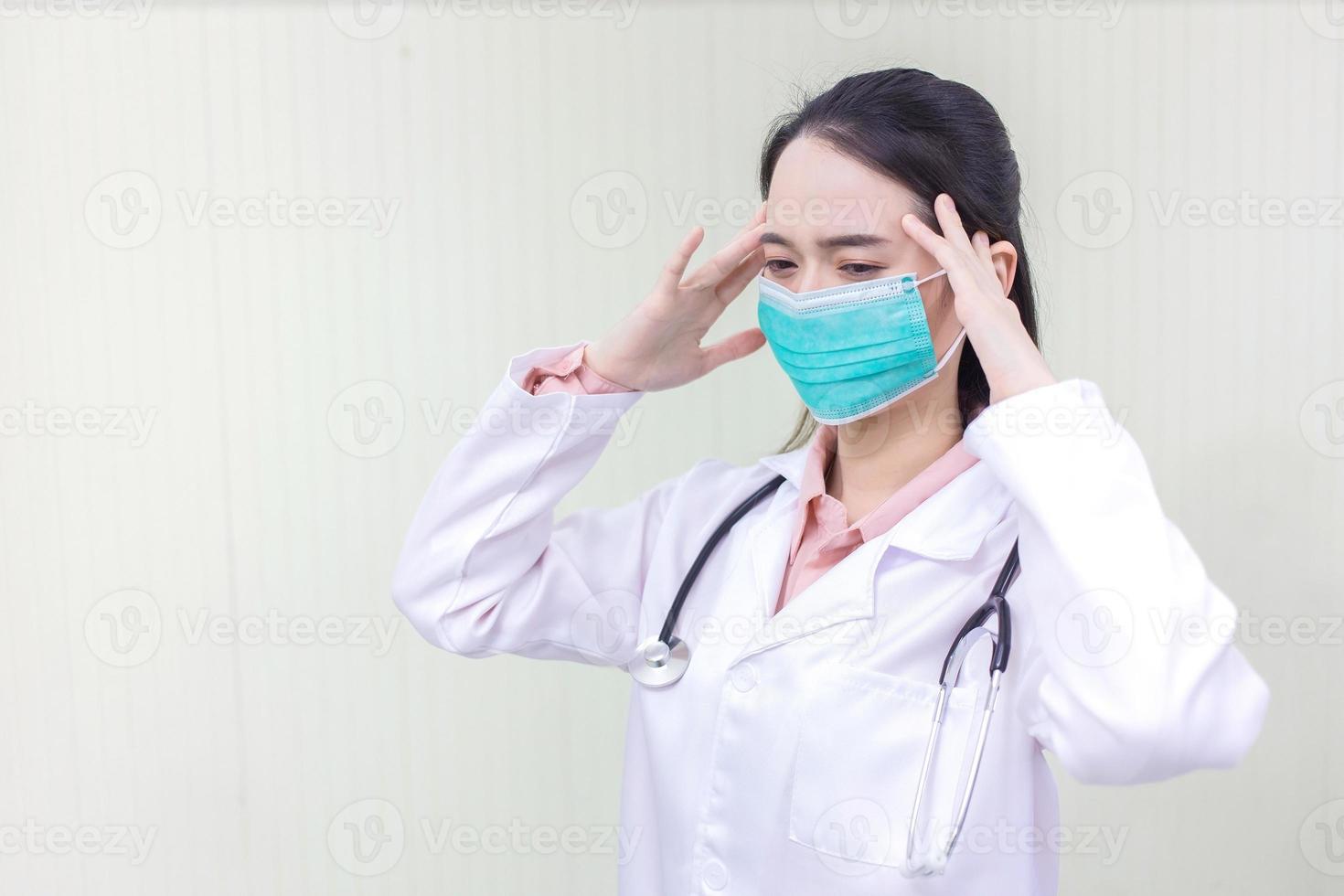 Asian female doctor Sitting in the examination room wearing a mask and pondering in  health care,pollution PM2.5,new normal and coronavirus protection concept. photo