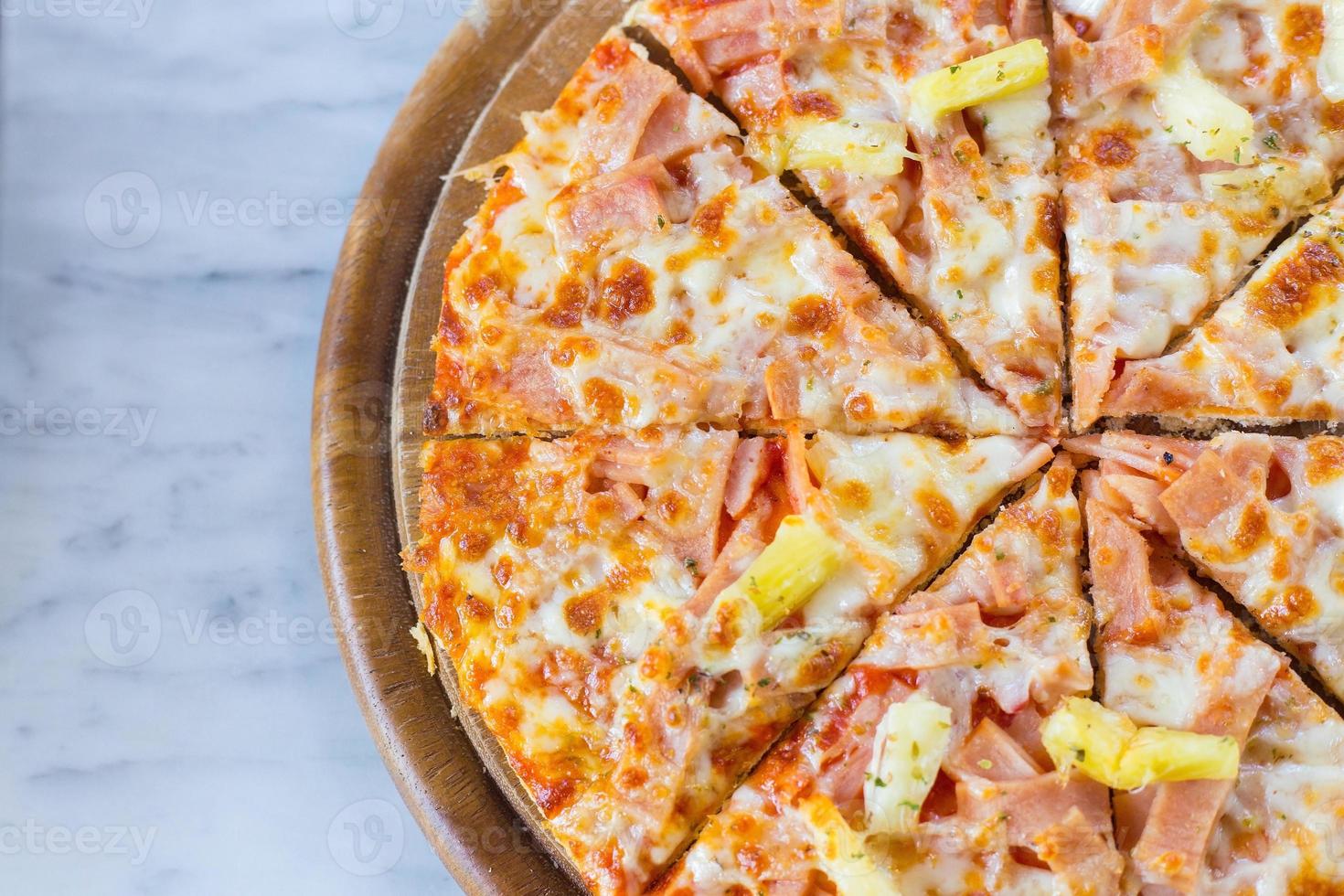 La pizza hawaiana es una comida italiana que se prepara con salsa de tomate, piña picada, jamón y queso. foto