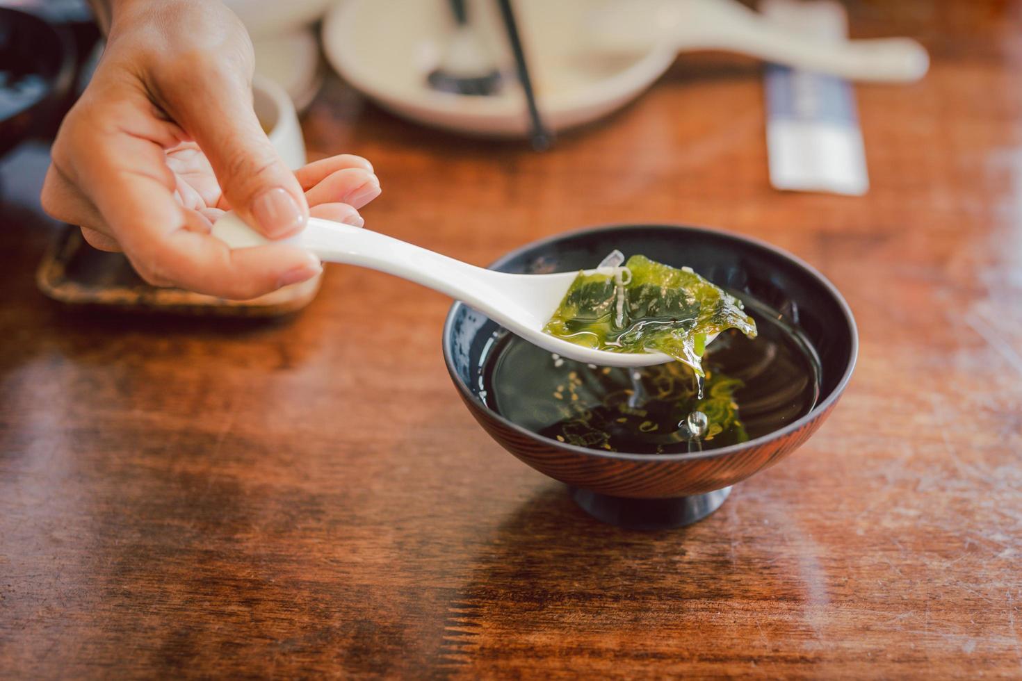 Hand with spoon eating traditional seaweed Japanese soup. photo