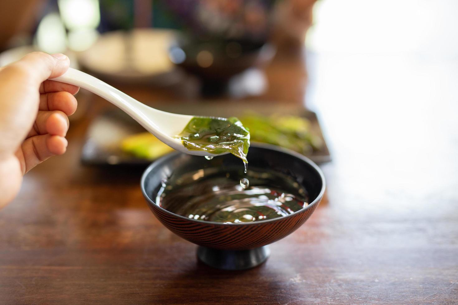 Hand with spoon eating traditional seaweed Japanese soup. photo