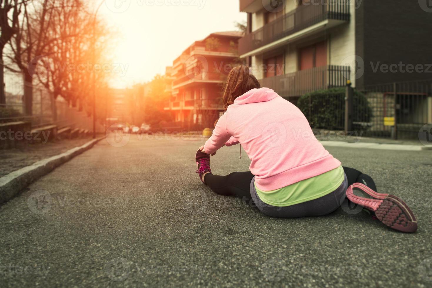 Girl does stretching out into the street in the city at dawn photo
