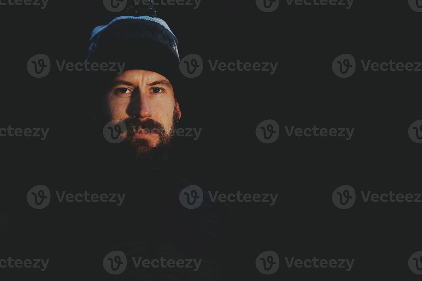 retrato de hombre con barba y gorra de lana sobre fondo negro foto