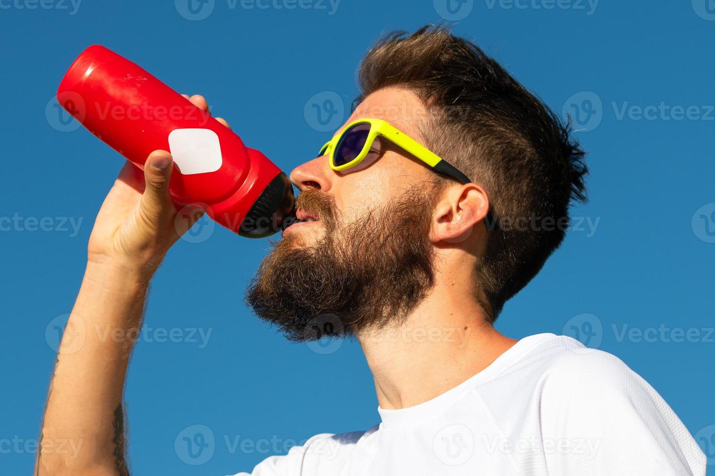 Sporty man drinks from your water bottle photo