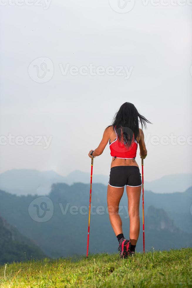 Sporty woman with nice body looks at the panorama in the mountains during on trekking photo