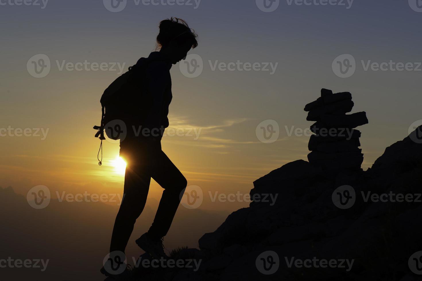 en una excursión al atardecer con colores de cuento de hadas hacia una chica en las montañas en las siluetas foto