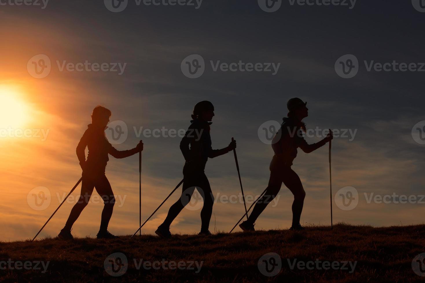 Nordic walking in silhouette at sunset photo