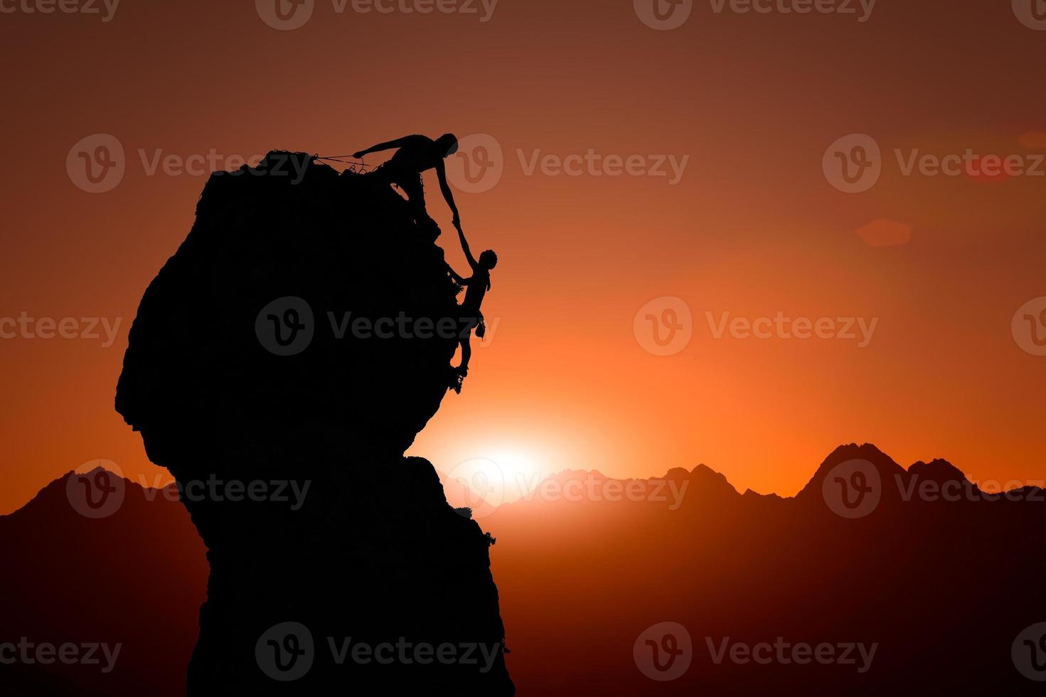 Team of climbers help to conquer the summit at sunset photo