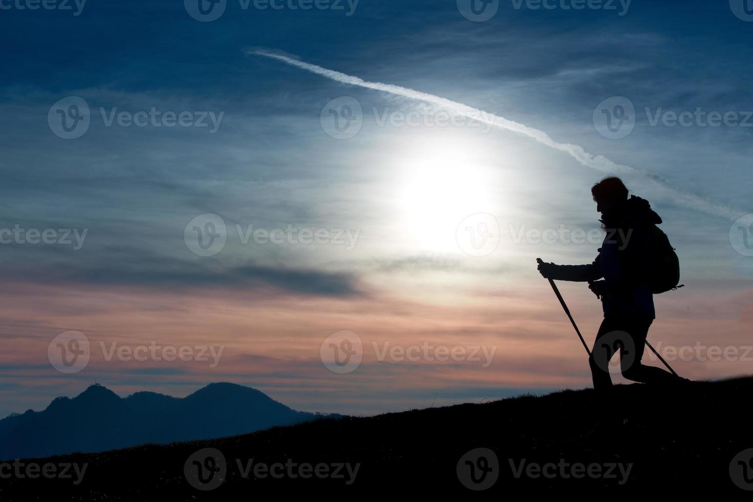 Silhouette of a girl on a mountain during a religious trek in a blue and orange sky. photo