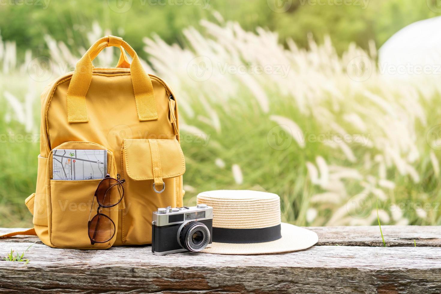 Travel backpack with traveler items on wooden bench with nature background and copy space photo