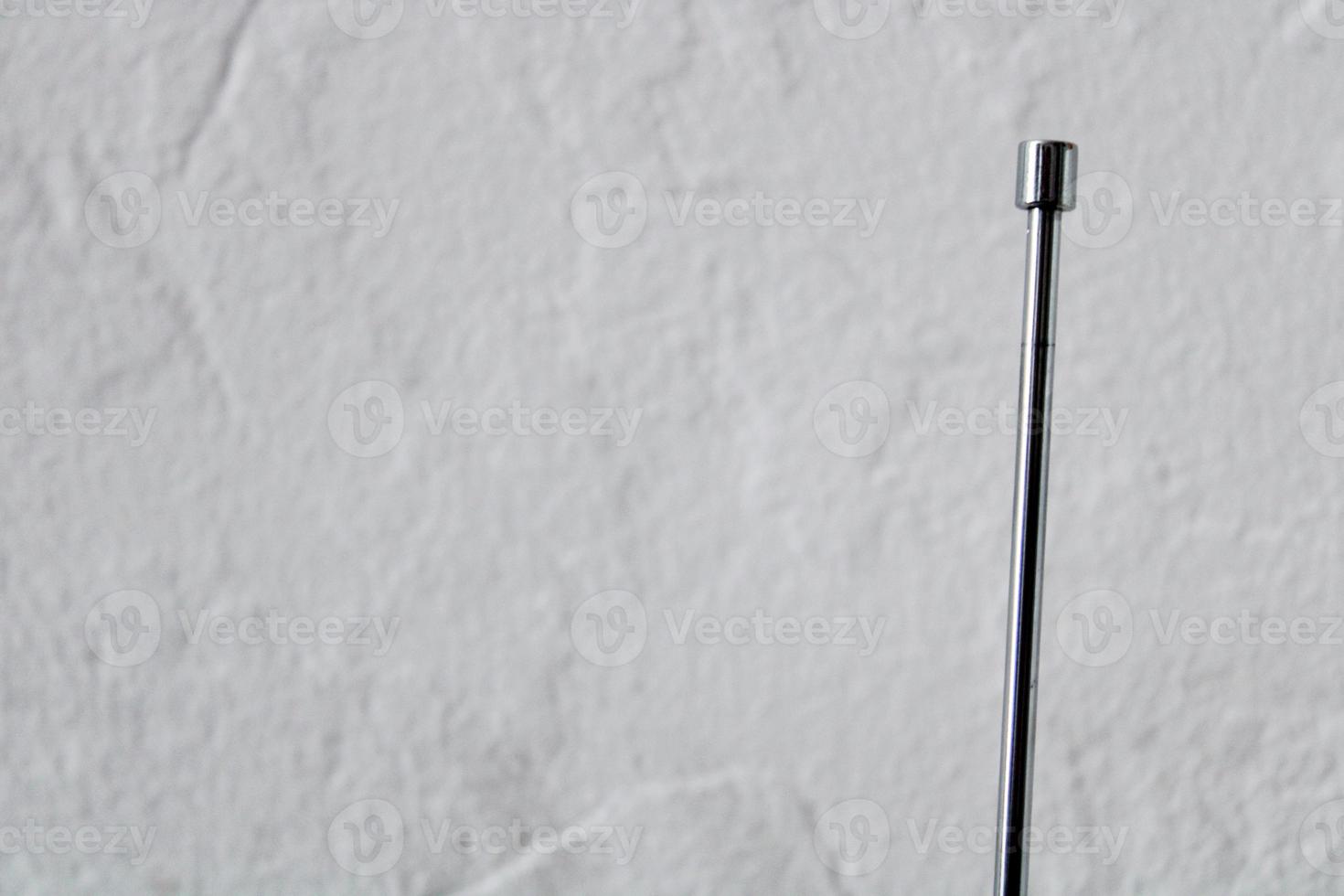 Metallic radio antenna with reflection on blurred white textured background, horizontal photo. Close up, decorative design element for banners, wallpaper photo