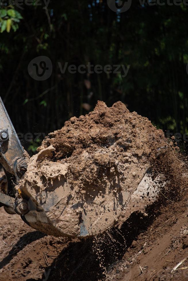 Closeup of bulldozer machine digging the ground and removing sand for excavation purpose photo