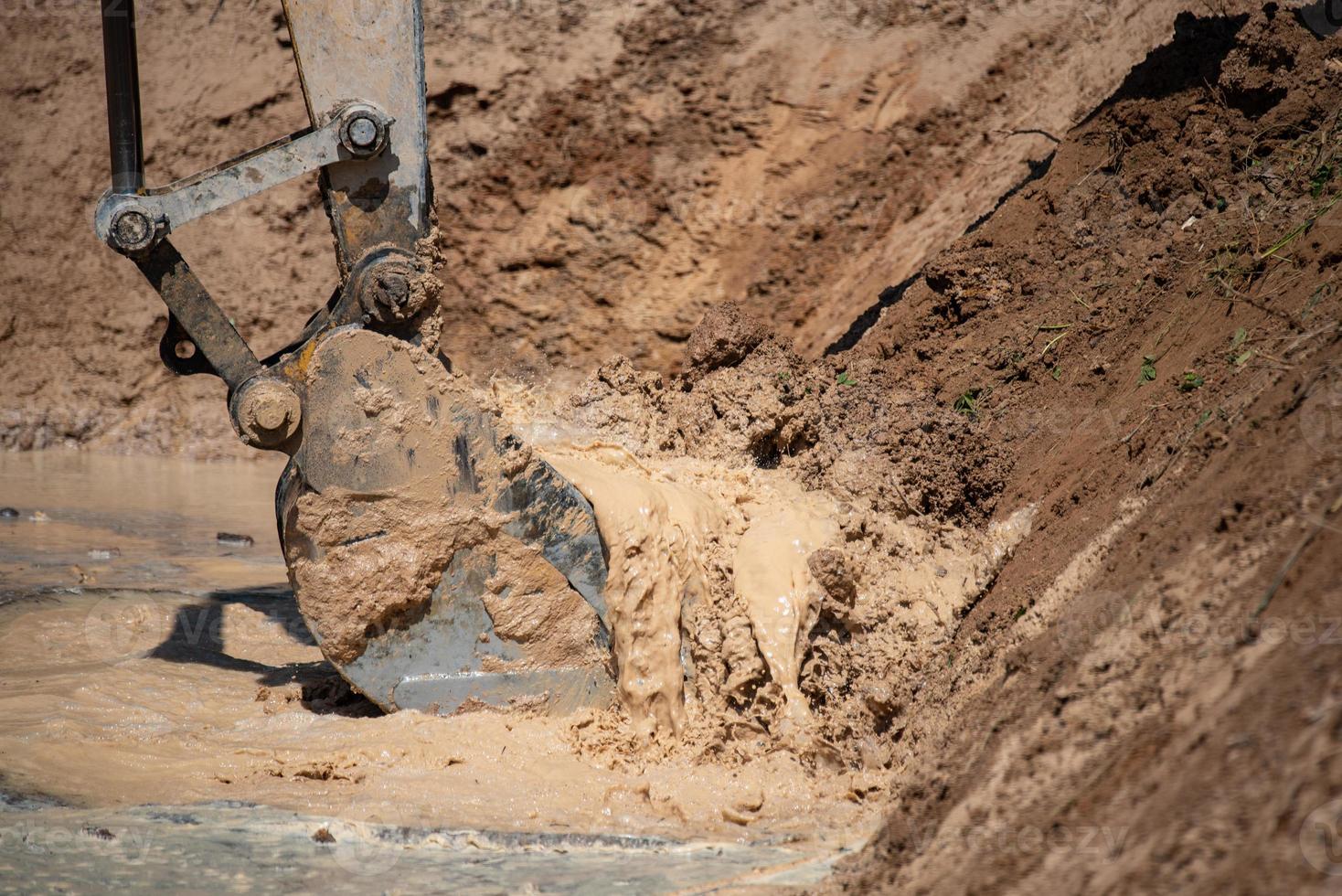 Closeup of bulldozer machine digging the ground and removing sand for excavation purpose photo