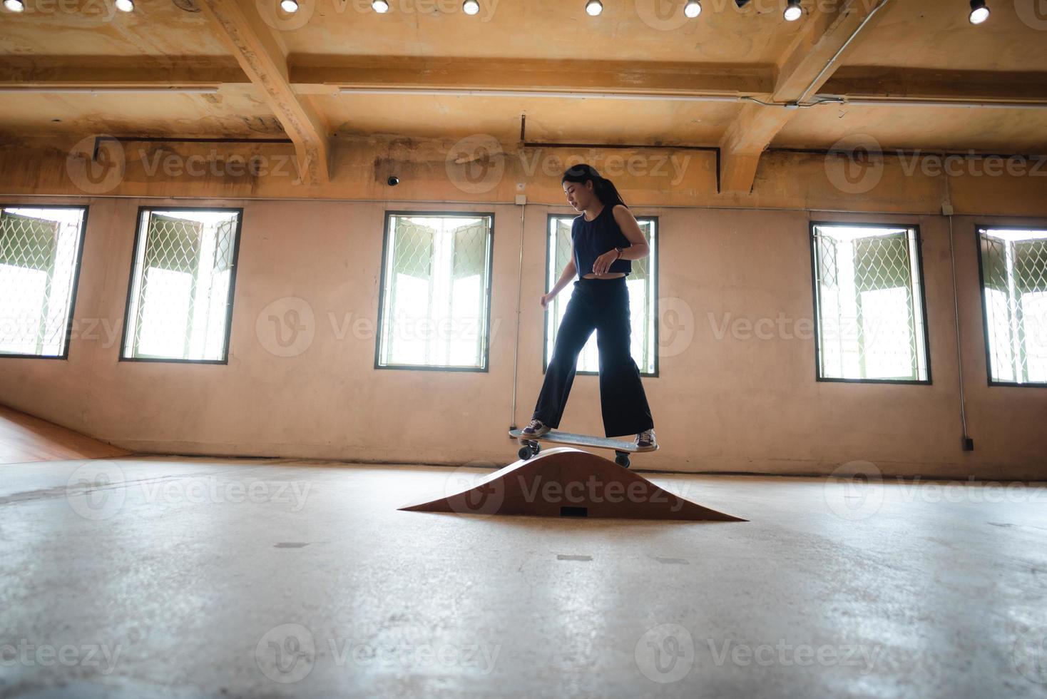 skater woman person playing skateboard in sport gym, young Asian woman are happy and fun with skateboarding lifestyle in city, teenage hipster female trendy fashion photo