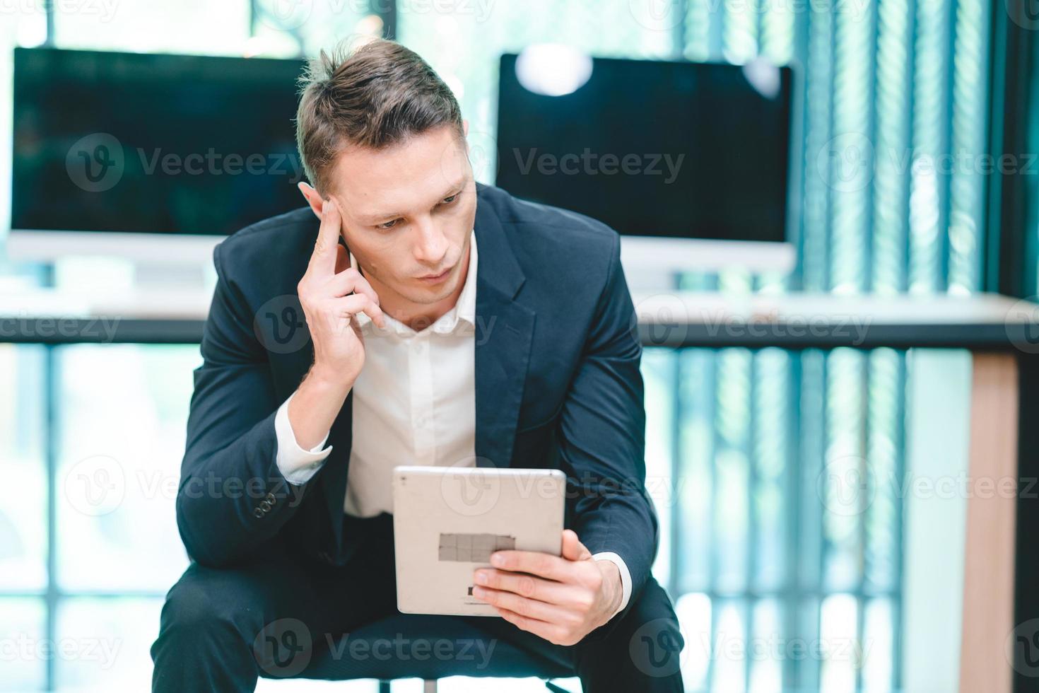 Serious and focused business man and entrepreneur in formal clothing working and reading file with female secretary and employee with headphones in meeting room in modern office photo