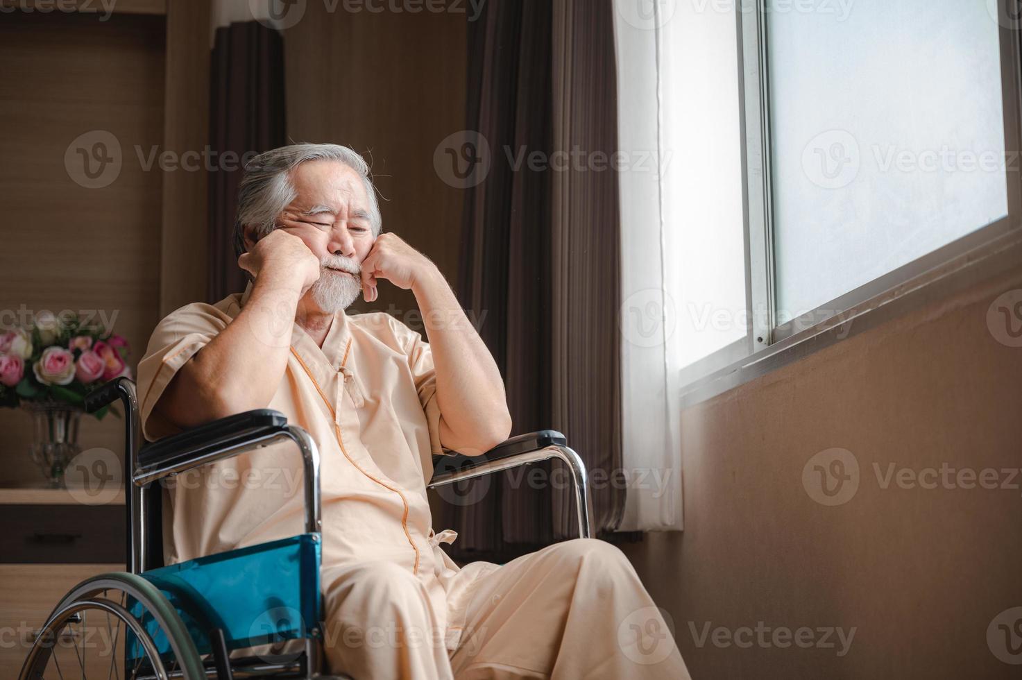 Senior male patient with grey hair sitting on wheelchair feeling depressed and lonely while thinking in hospital private room photo