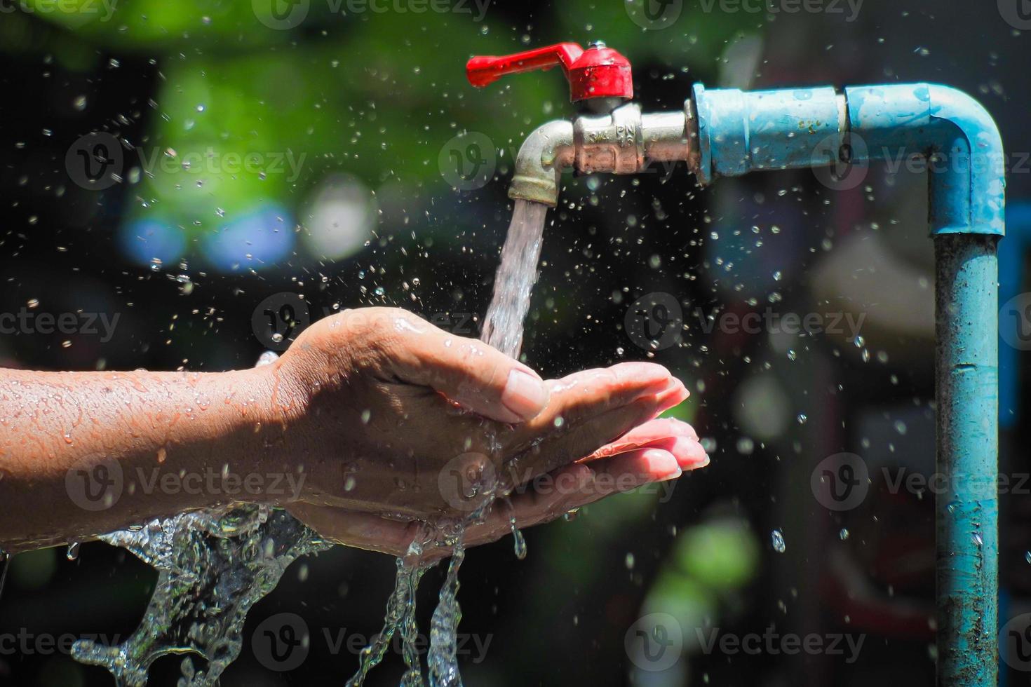 Water concept in everyday life. Hands supporting the water flowing from the faucet. water splashing from the tap photo