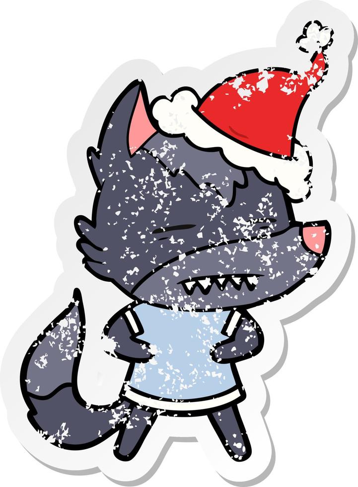 distressed sticker cartoon of a wolf showing teeth wearing santa hat vector