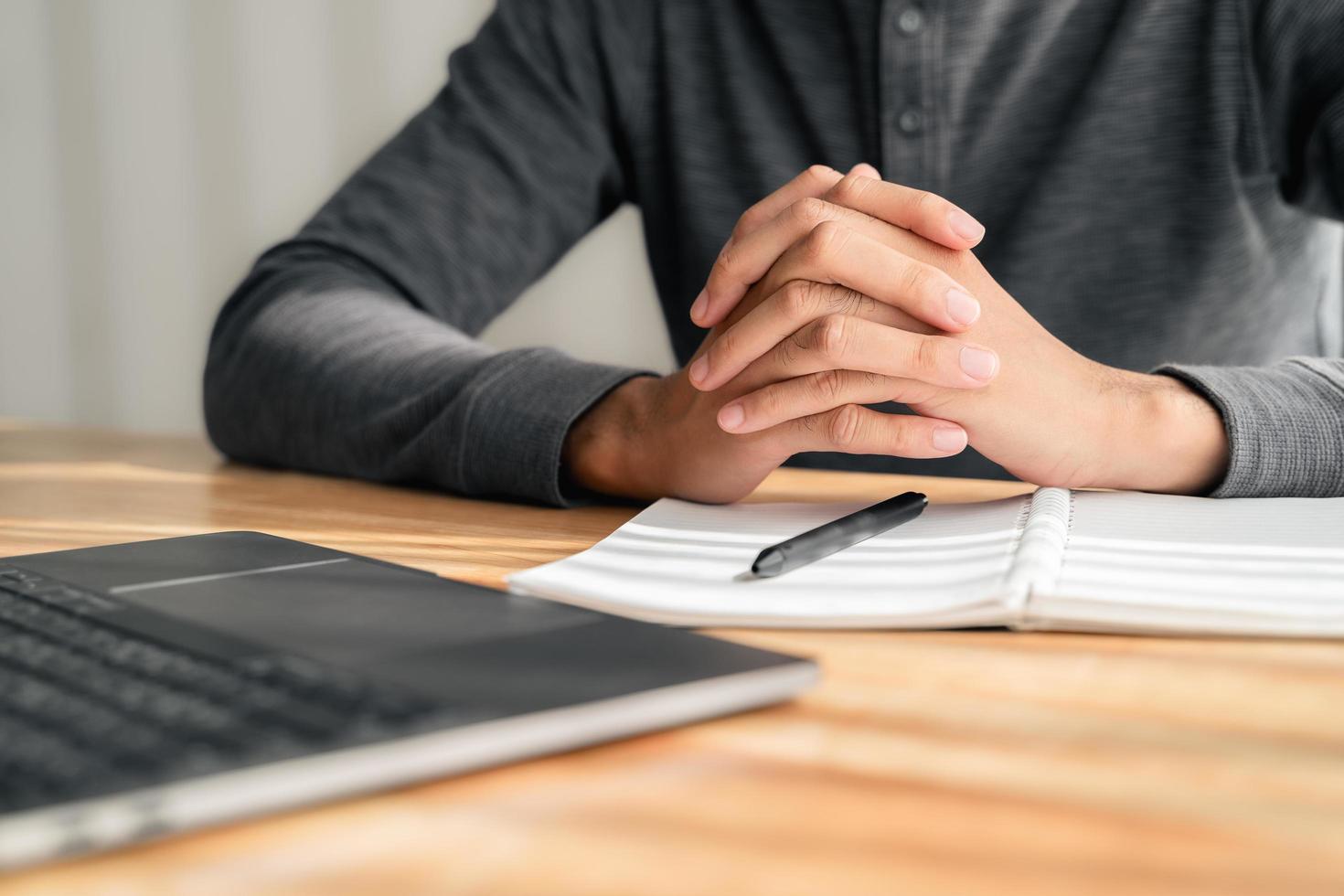 Close up of man clasped hands clenched together on table, businessman preparing for job interview, concentrating before important negotiations, thinking or making decision, business concept photo