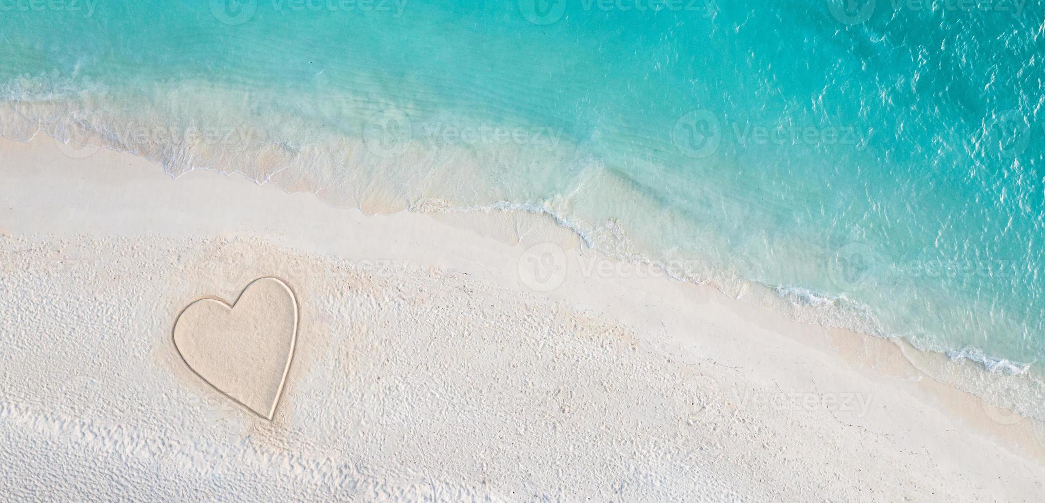 Perfect drawing of heart shape in soft sand beautiful seascape background. Romantic Valentine's day or love beach scene, top aerial view. Romance, honeymoon in vacation, summer travel. Idyllic nature photo