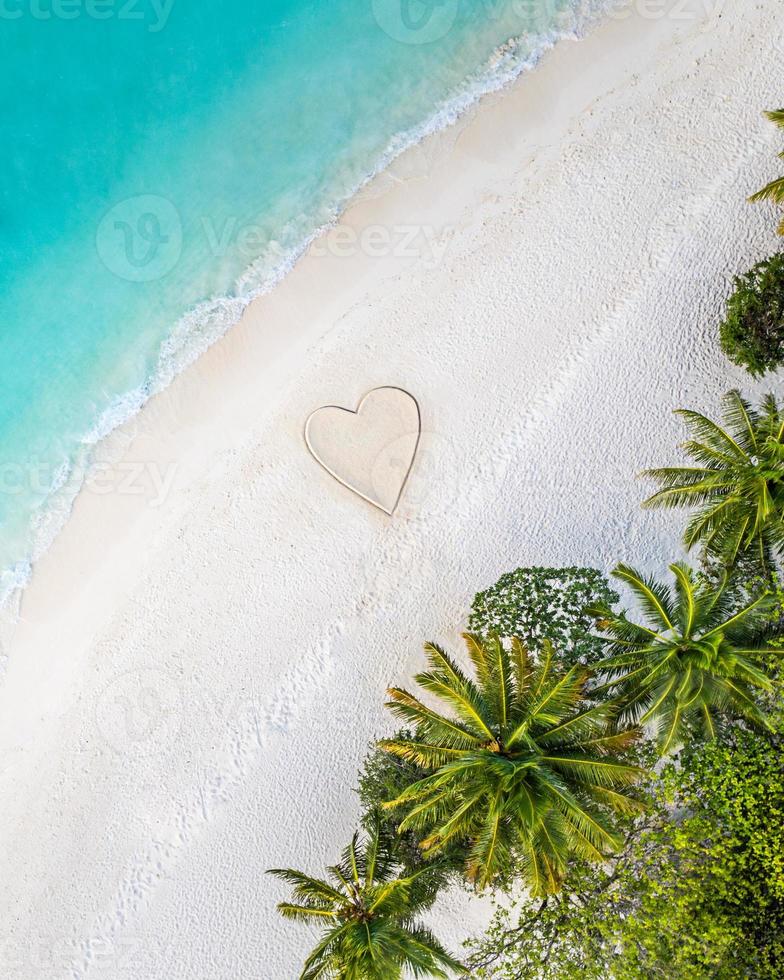 Perfect drawing of heart shape in soft sand beautiful seascape background. Romantic Valentine's day or love beach scene, top aerial view. Romance, honeymoon in vacation, summer travel. Idyllic nature photo