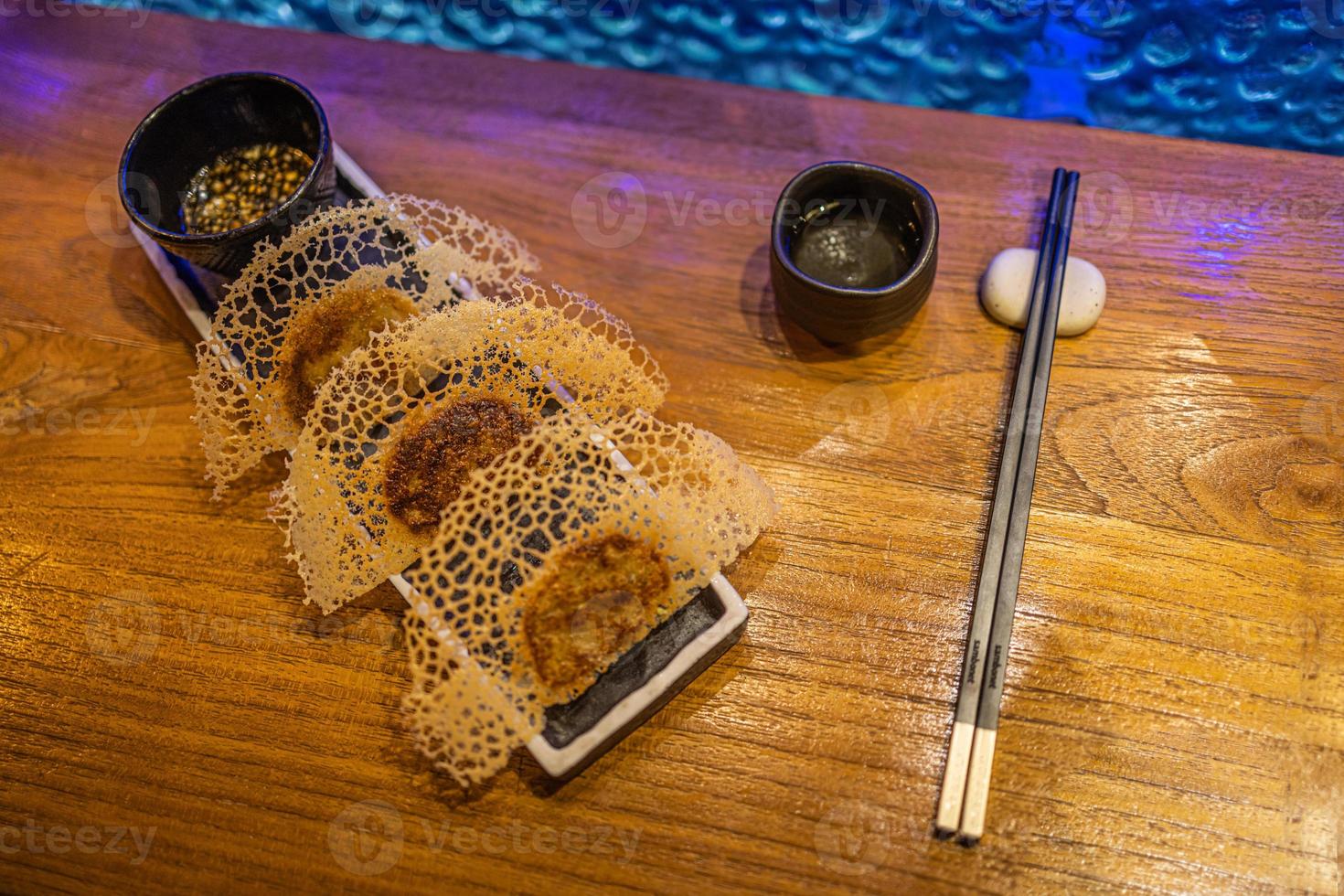 Fried dumplings Gyoza in a frying pan, soy sauce, and chopsticks on a brown wooden background, top view photo