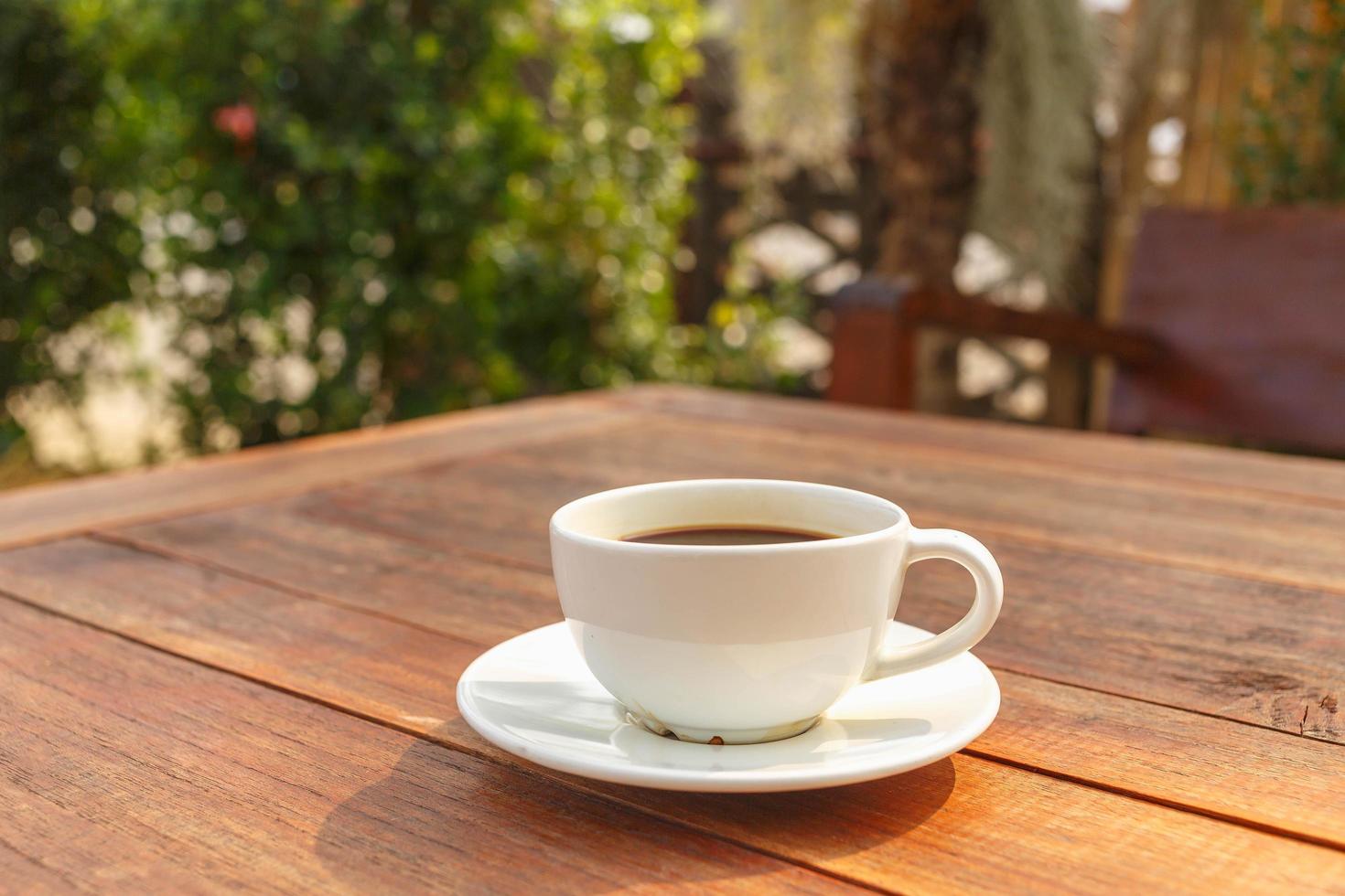 cup of coffee on wooden table in morning sun photo