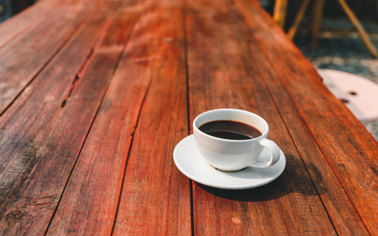 cup of coffee on wooden table in morning sun photo